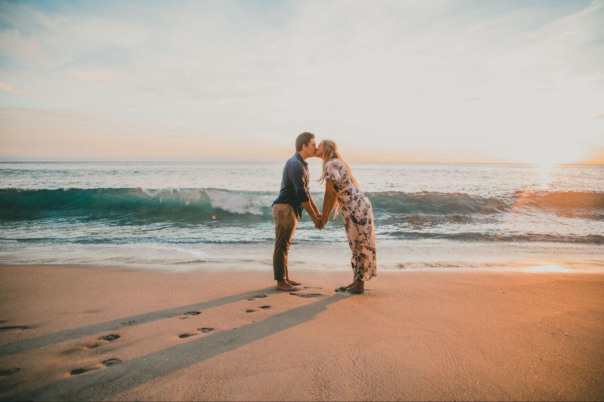 A couple kisses at the beach at sunset