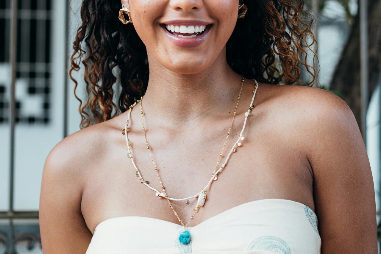 A close-up of a fashionable young woman wearing an elegant and distinctive necklace stack.