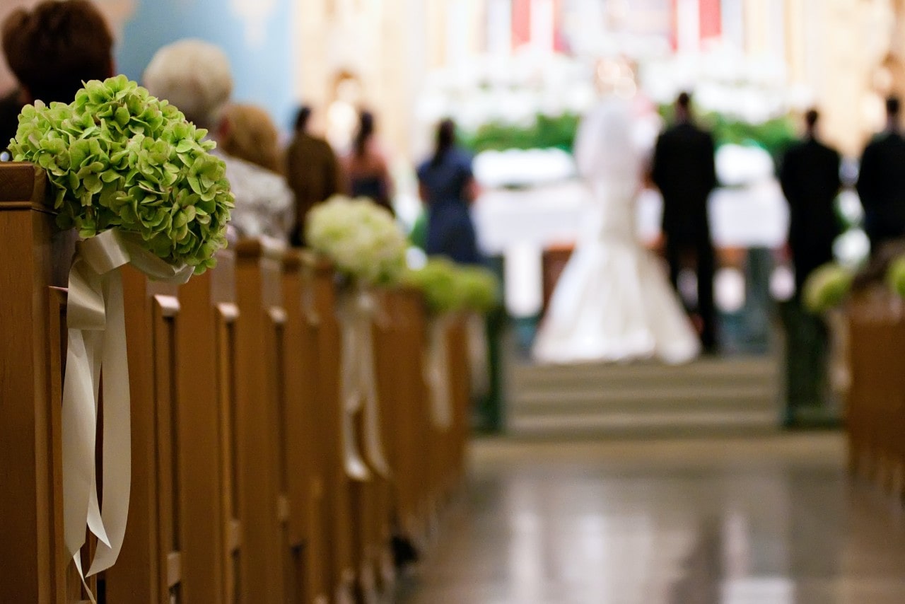 A blurry picture of a couple standing in the aisle in the church.