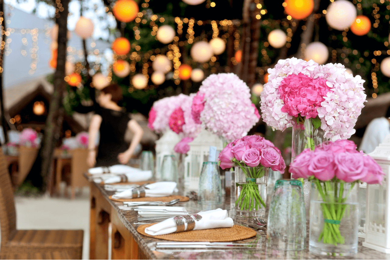A wedding venue, specifically the table, decorated with pink roses and hydrangeas.