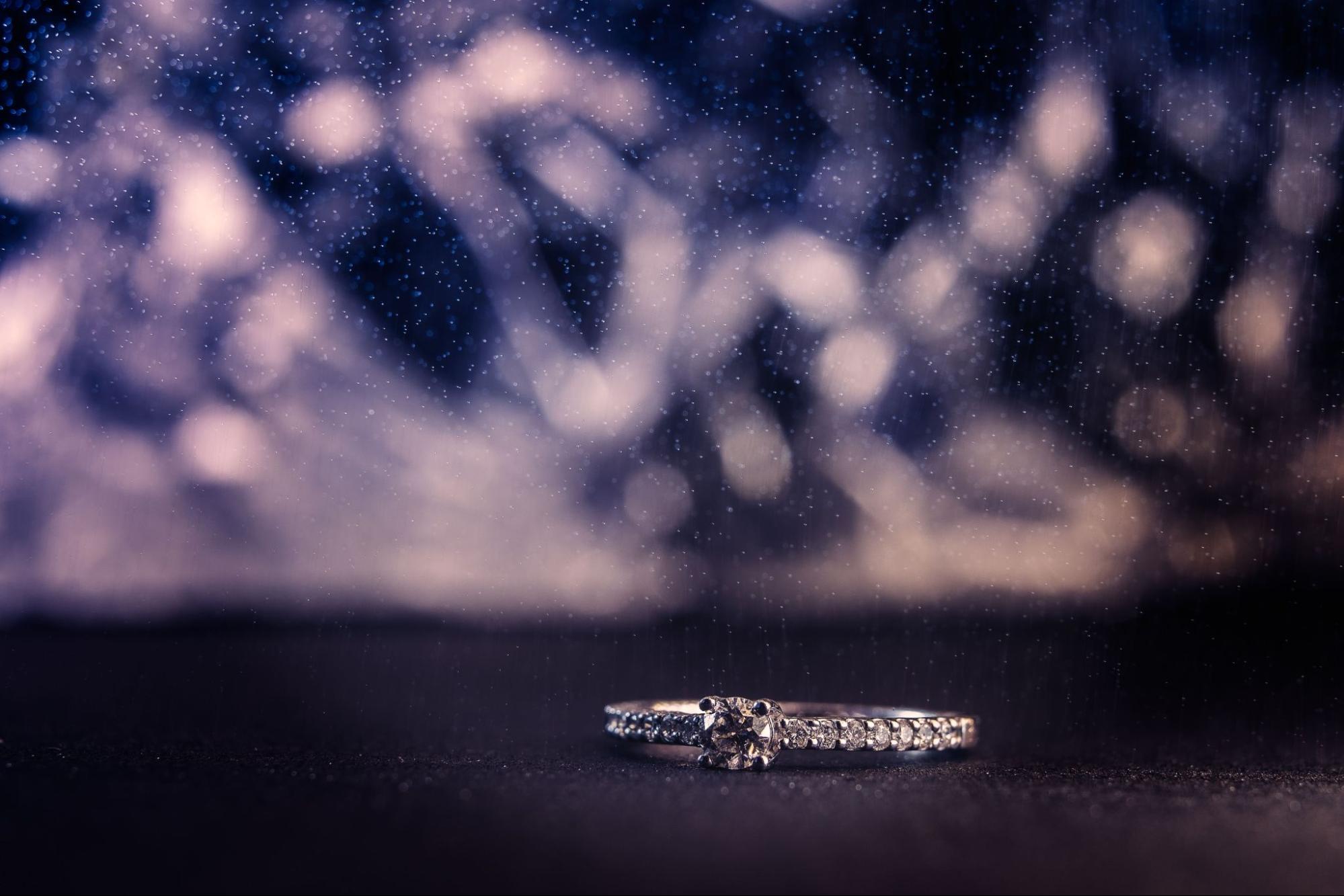 a white gold diamond side stone engagement ring lying on a dark surface