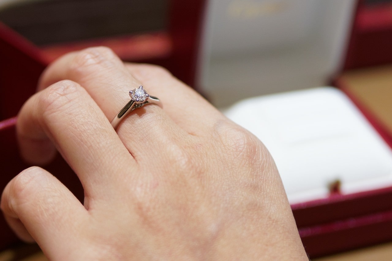 a hand wearing a white gold diamond fashion ring on its middle finger