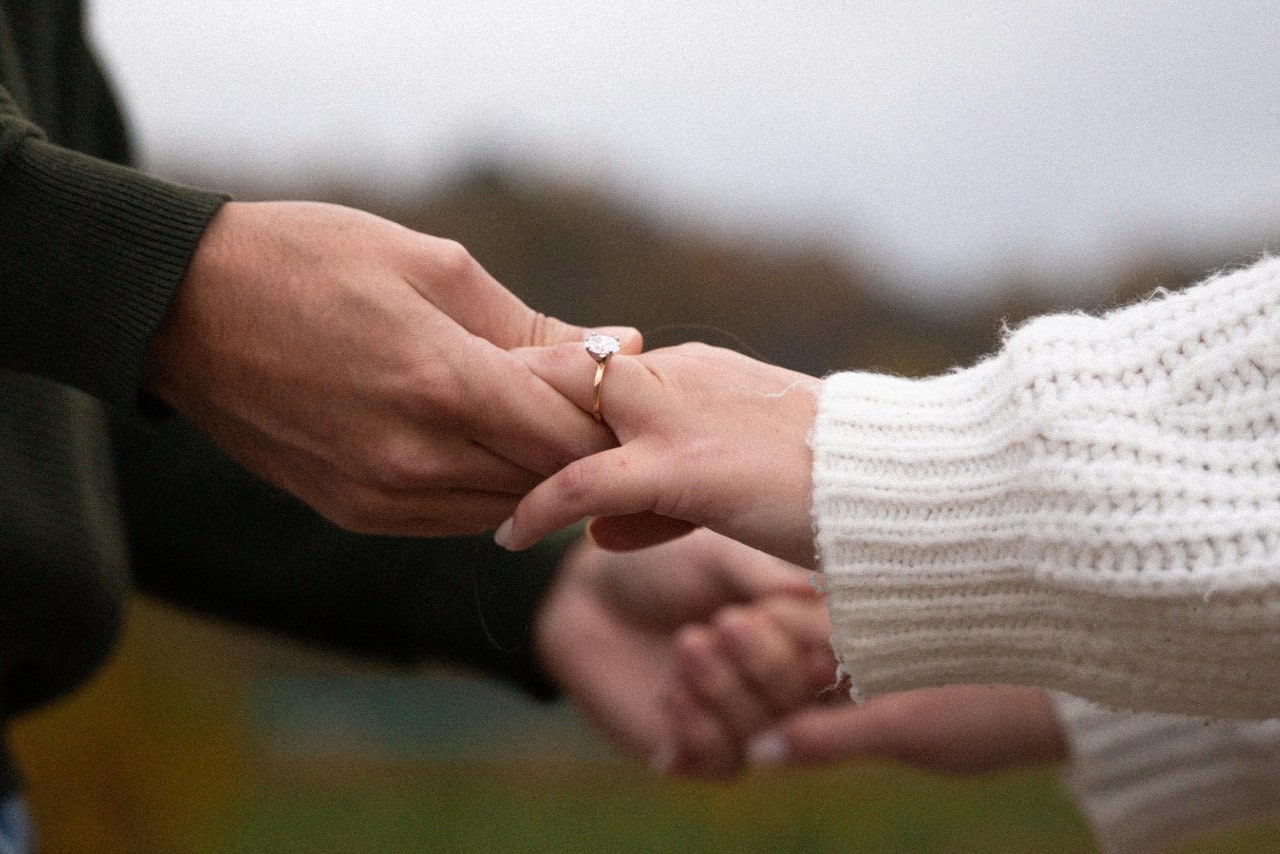 A couple holding hands with a focus on the yellow gold solitaire engagement ring