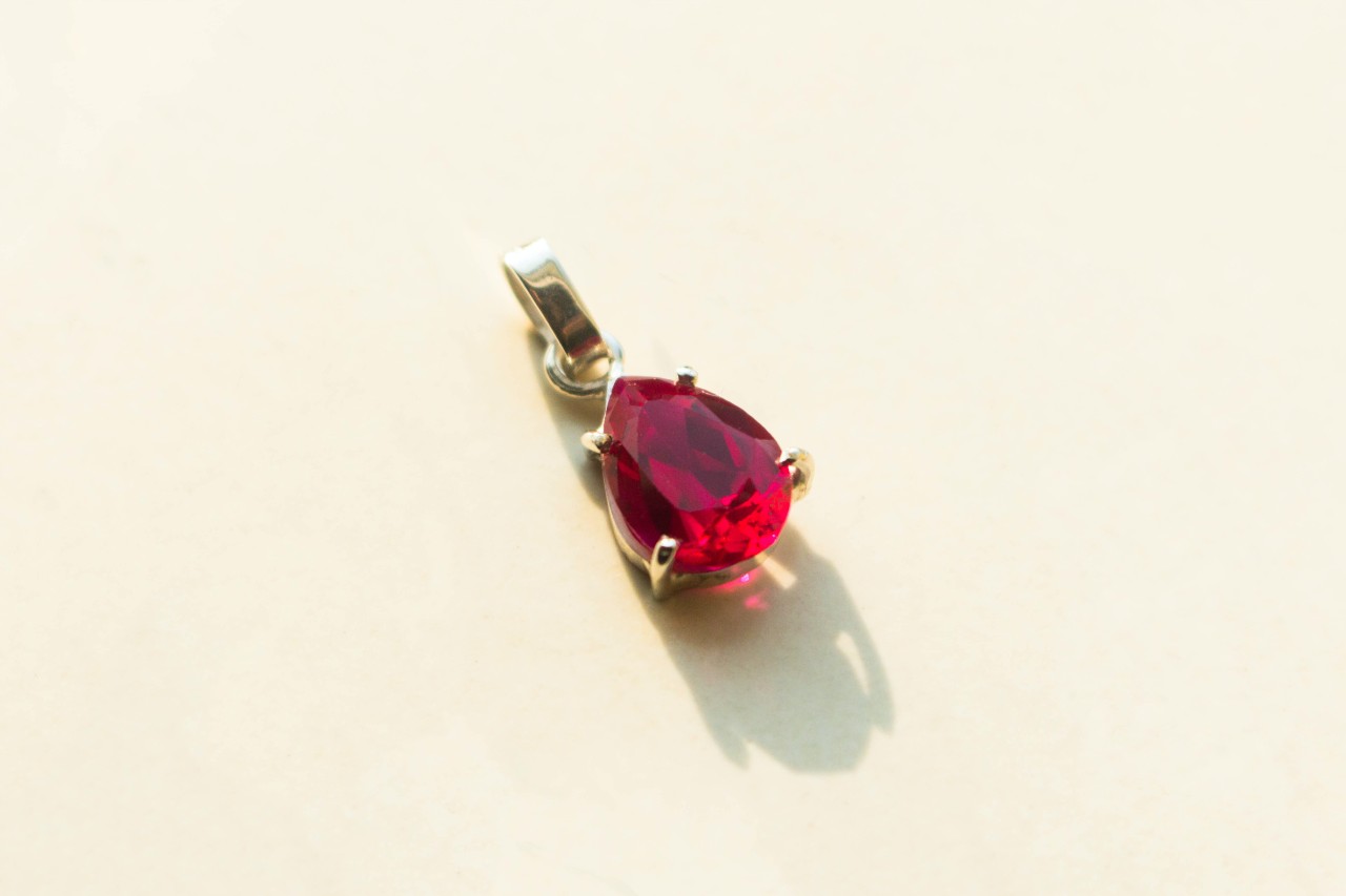 A pear shaped garnet pendant against a beige background