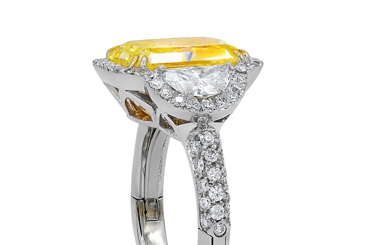 A luxurious white gold ring with a large yellow diamond atop, surrounded by smaller clear diamonds.
