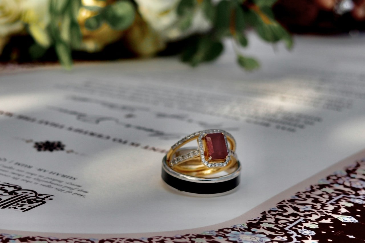 a stack of wedding bands and an engagement ring sitting on a wedding invitation