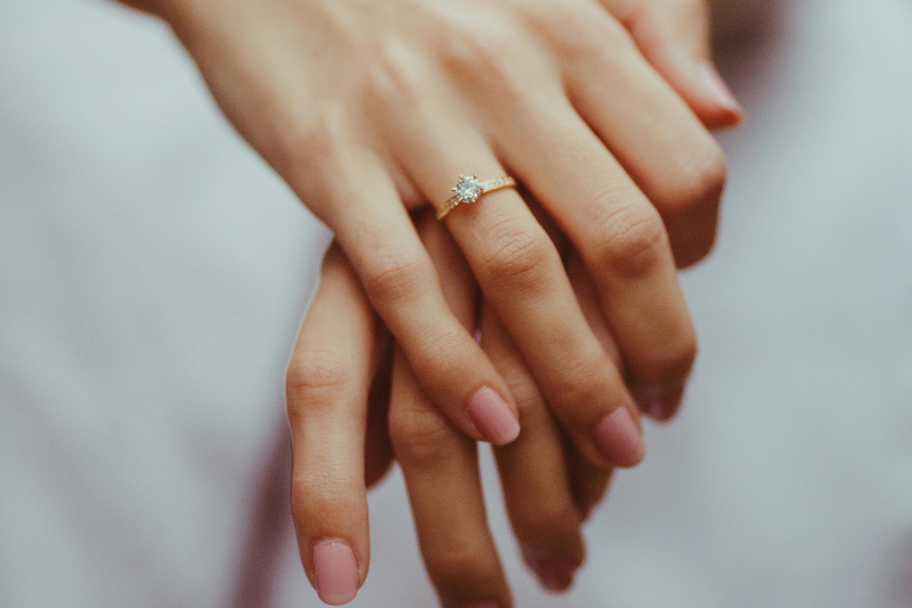 A side stone yellow gold engagement ring on a woman’s hand