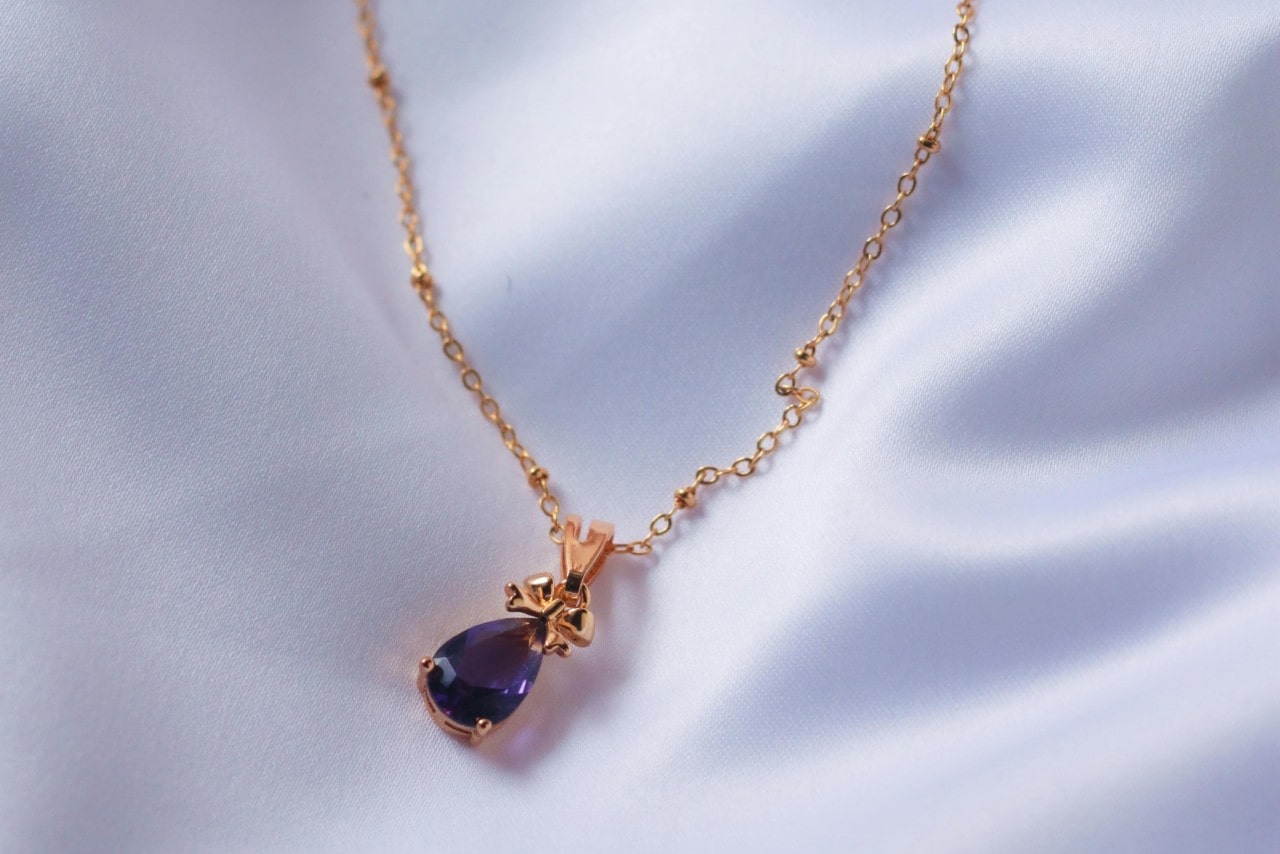 a rose gold necklace with an amethyst pendant