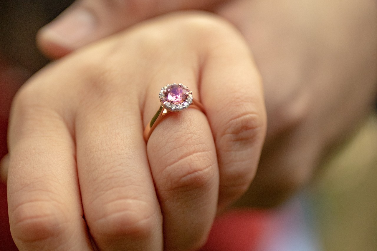 a close up of a lady’s hand wearing a diamond engagement ring