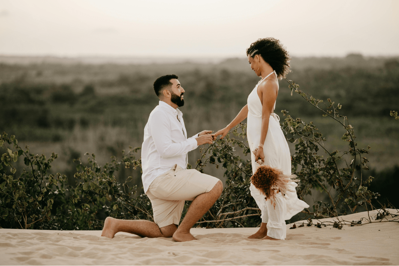 a man proposing to a woman in a sandy overlook spot