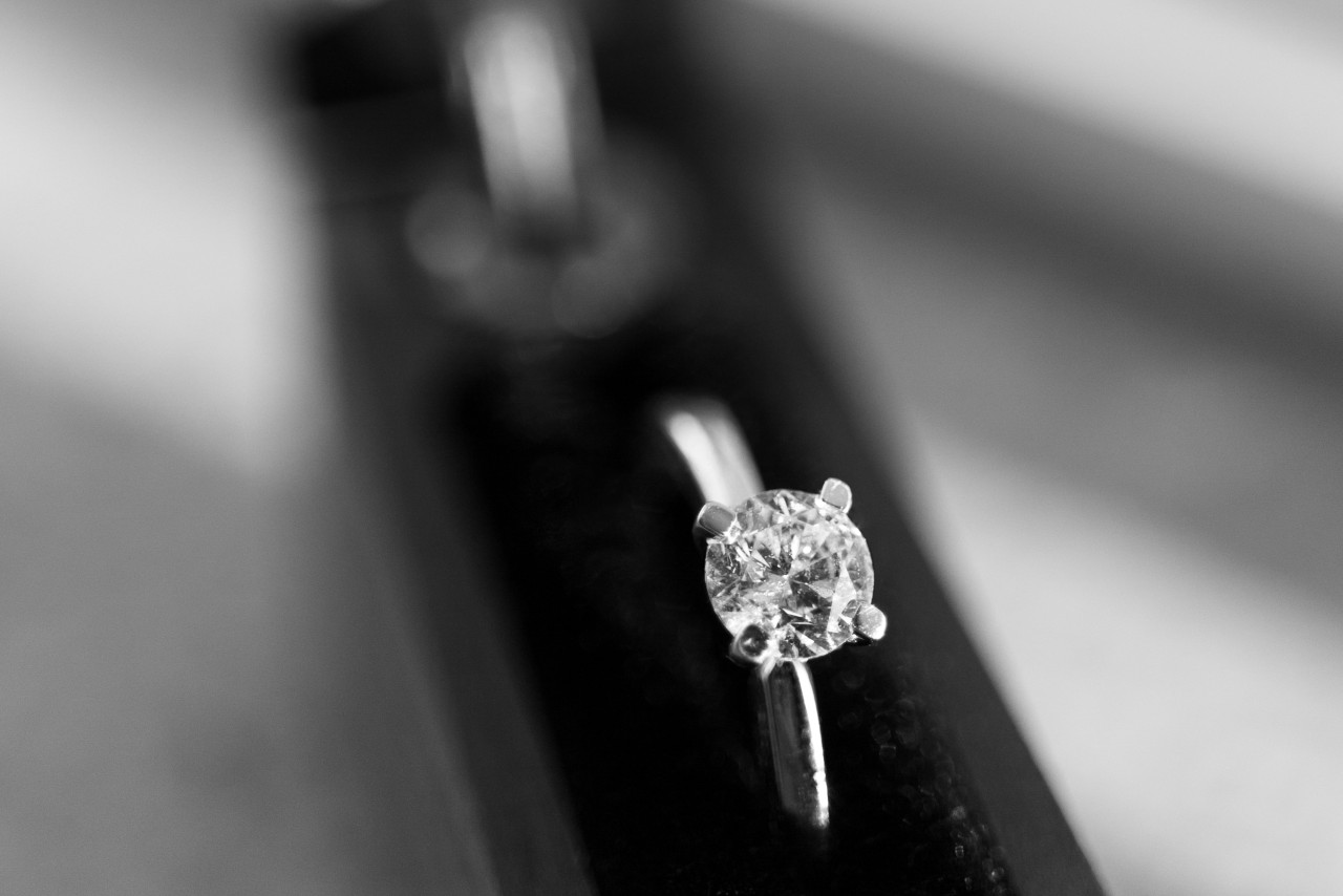 A black and white close-up of a simple yet elegant solitaire engagement ring.