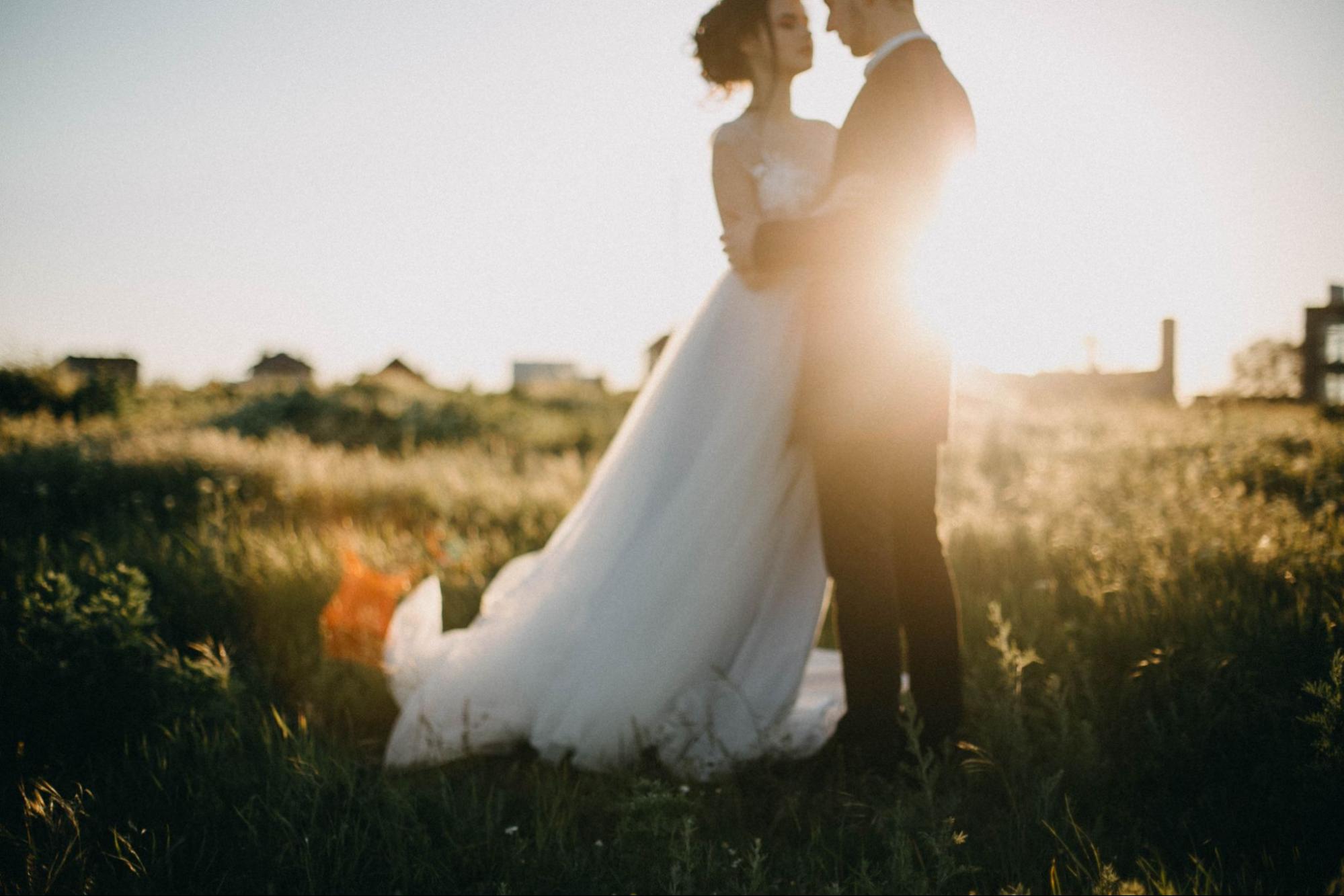 A view of a newlywed bride and groom in each other's arms at sunset.