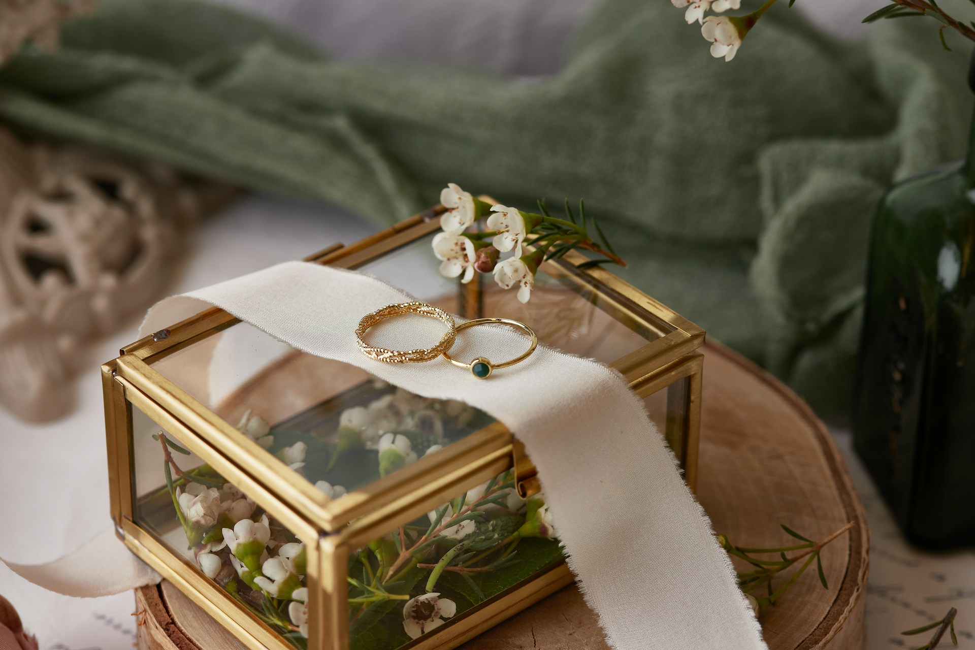 A view of a delicate engagement ring and wedding band displayed atop a glass jewelry box.