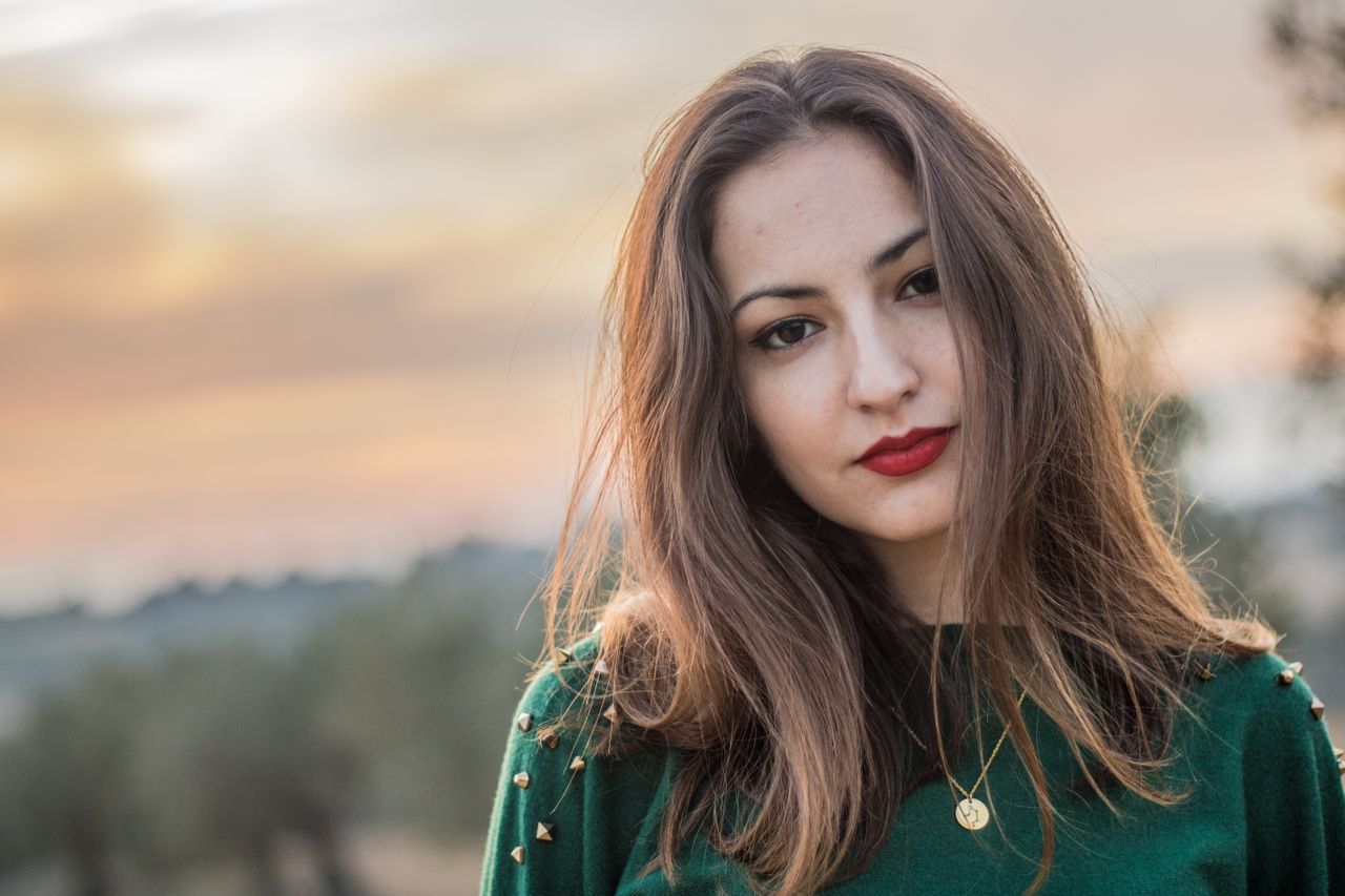 A woman wearing a gold medallion necklace at sunset A woman wearing a gold medallion necklace at sunset