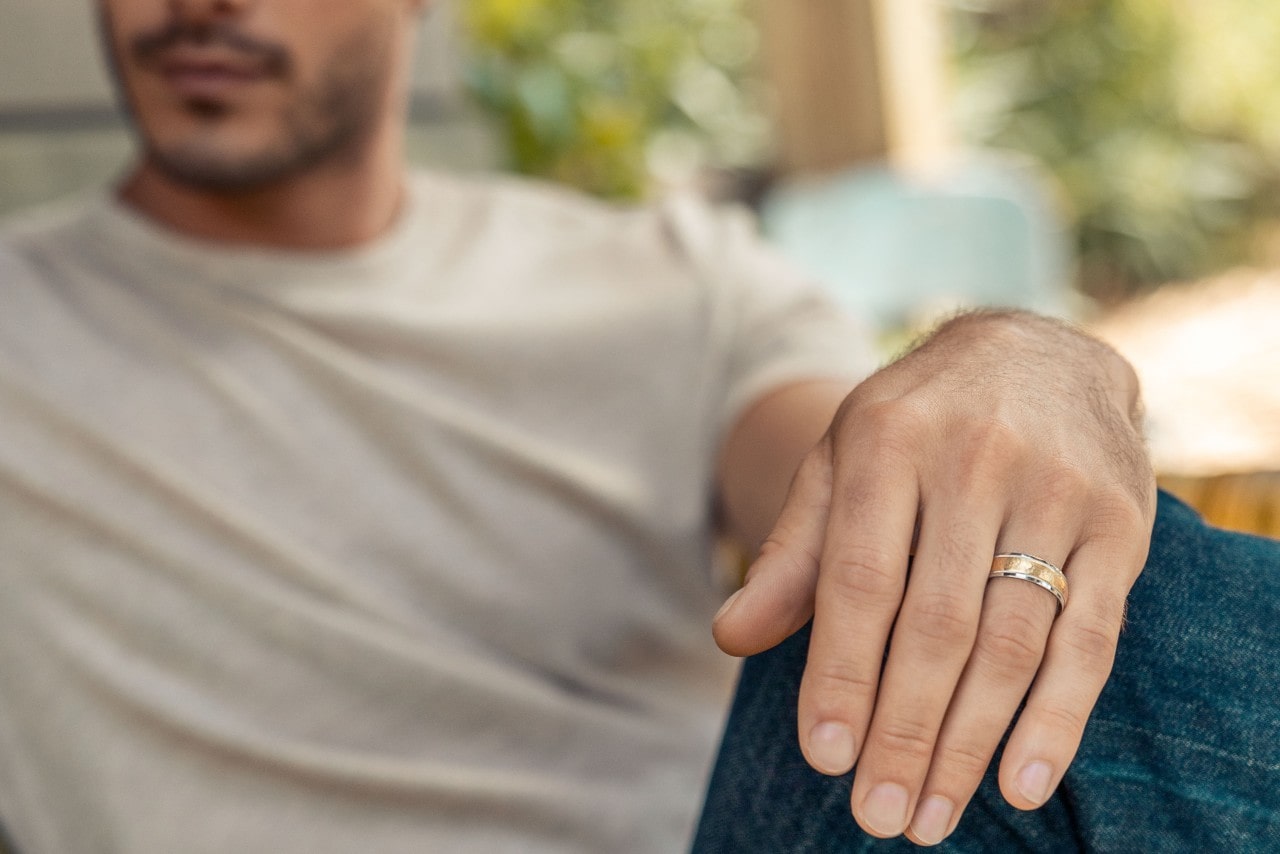 A close up of a man’s hand with a TACORI wedding band using mixed metals and a clean polish.