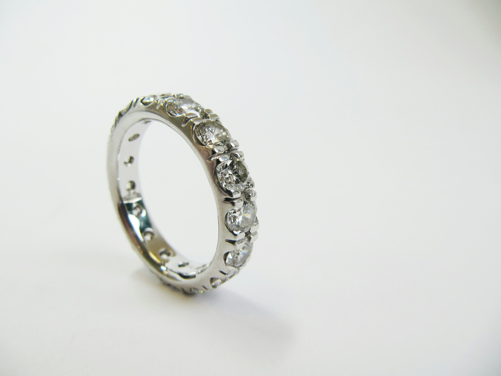A platinum diamond wedding band stands on a white background.