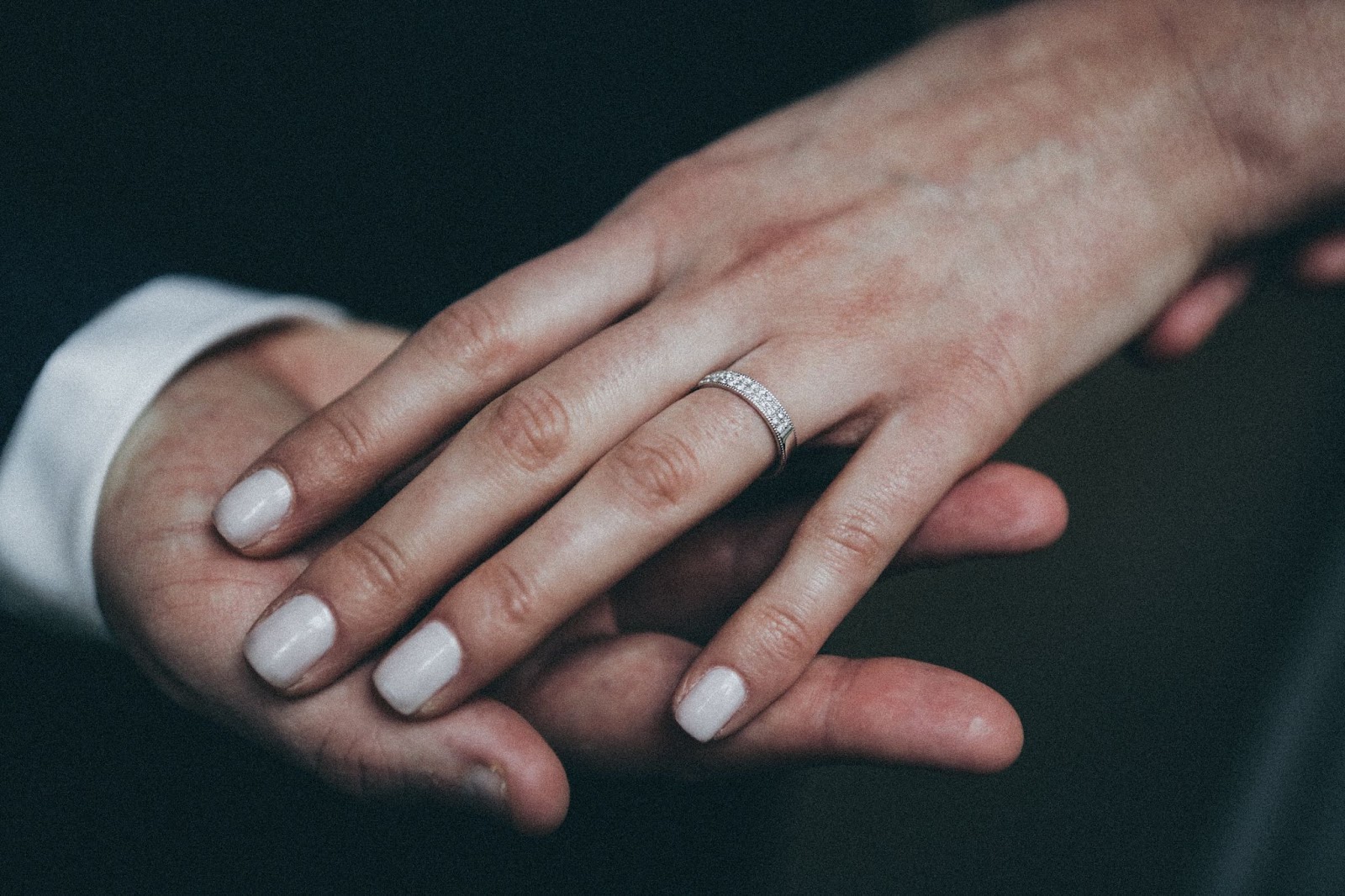 Two people holding hands, with the lady's wearing a diamond wedding band Two people holding hands, with the lady's wearing a diamond wedding band