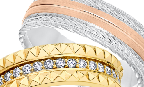 A close-up of two distinctive wedding bands, a ladies band from Michael M and a men’s band from ArtCarved, both available at Rogers Jewelry Co.