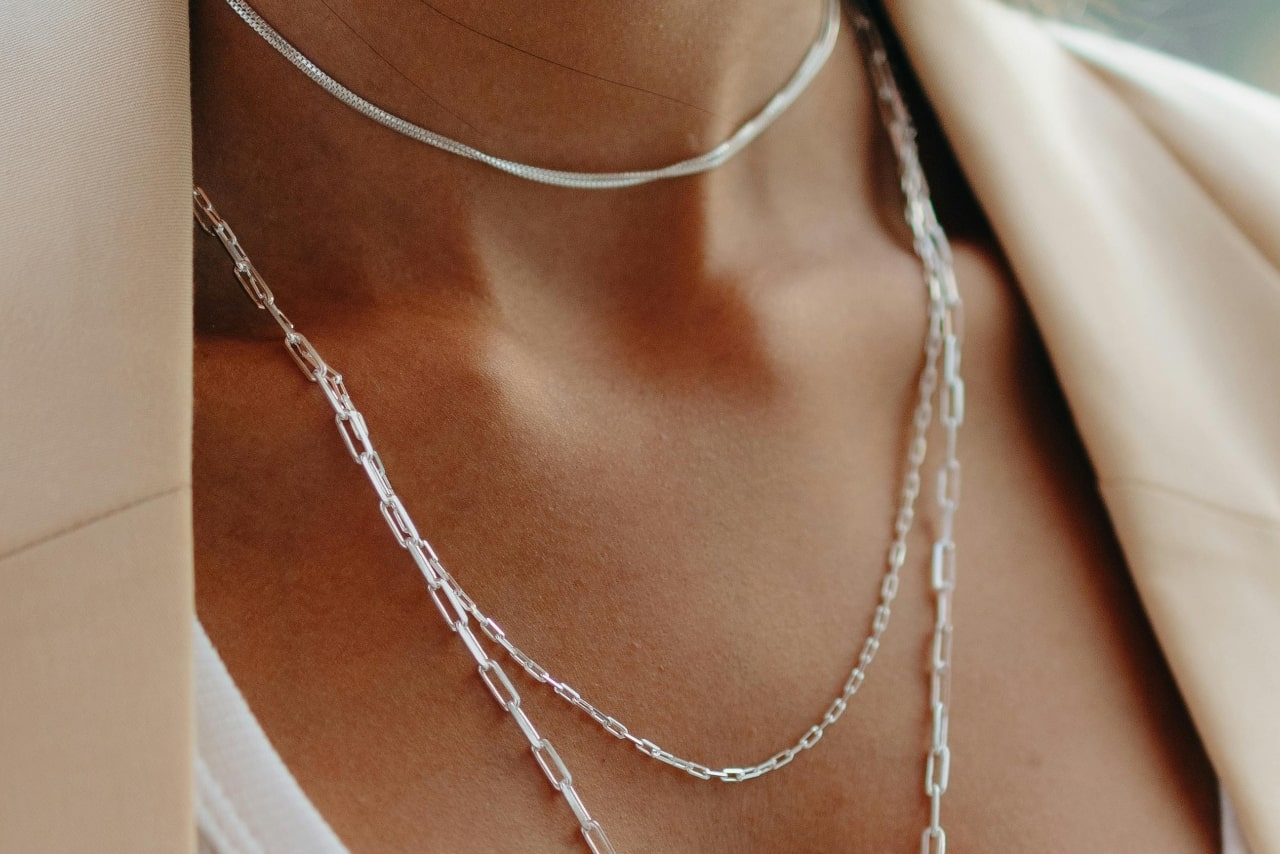 A woman wearing three dainty platinum chain necklaces