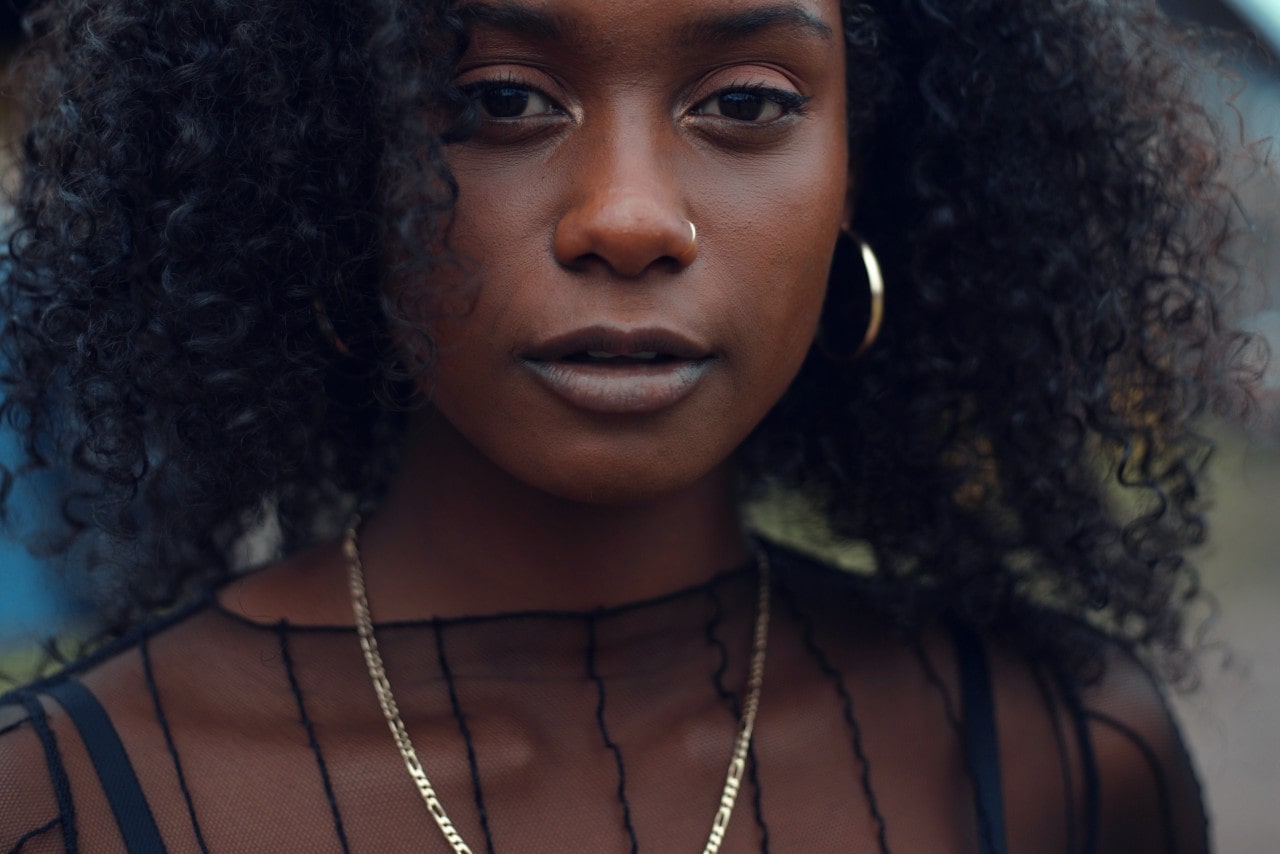 A woman in a sheer black top and a chain necklace.