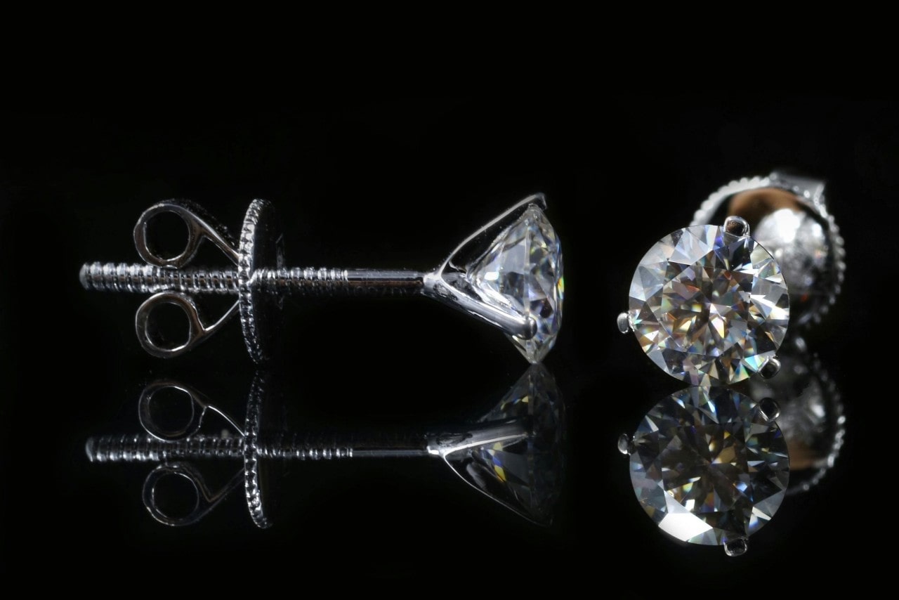 A close-up of elegant diamond studs on a black background.