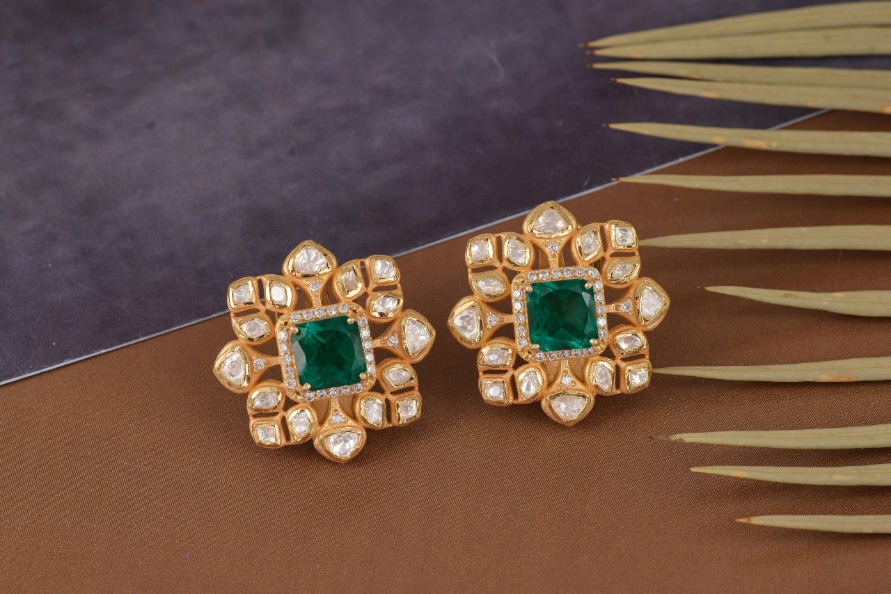 A close-up of elegant and distinctive diamond and emerald stud earrings.
