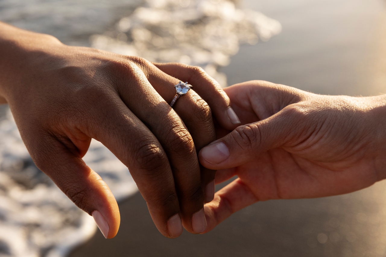 Close up of couple holding hands wearing engagement ring Close up of couple holding hands wearing engagement ring