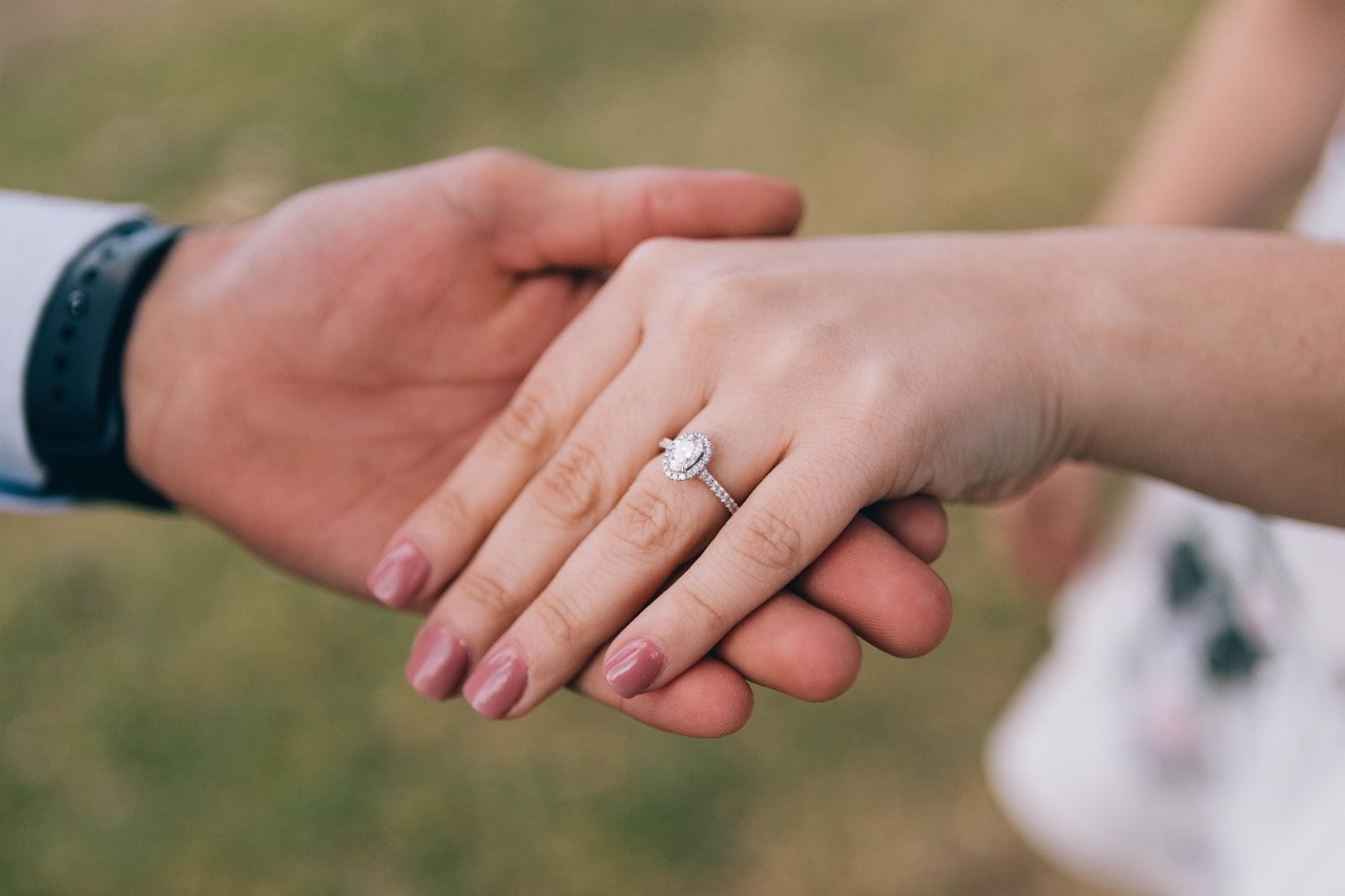 man holding a woman’s hand wearing an engagement ring