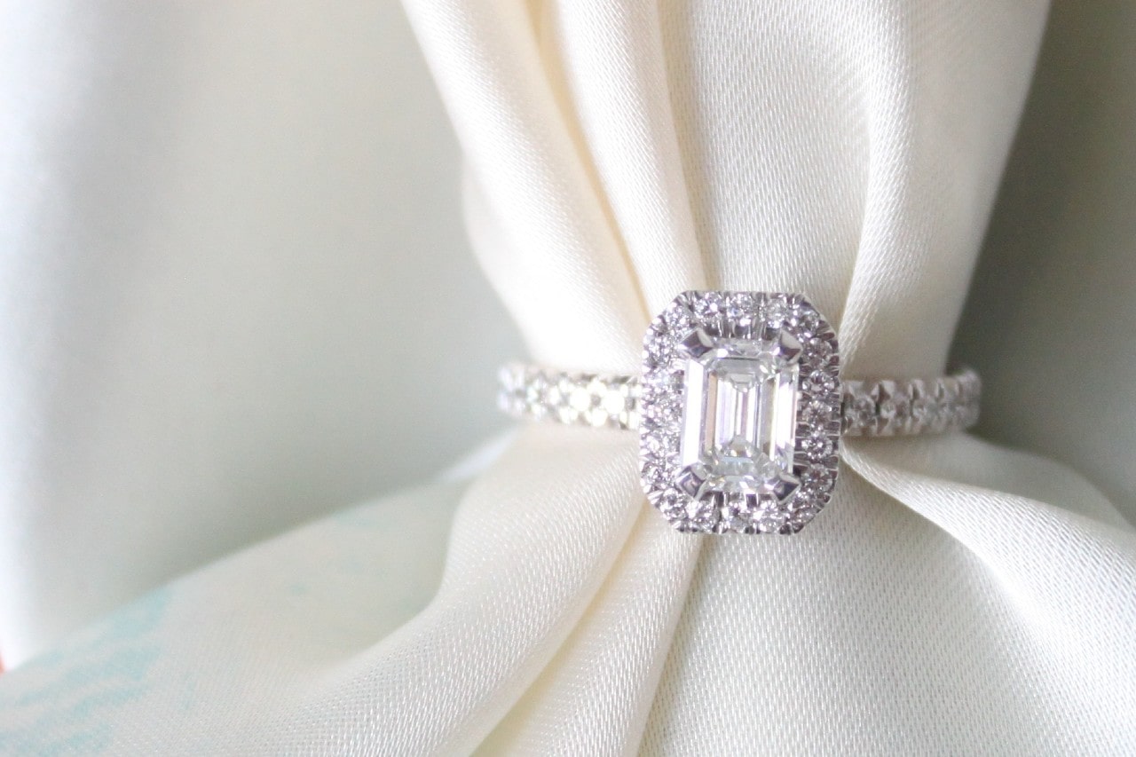 emerald cut halo engagement ring wrapped around a white cloth