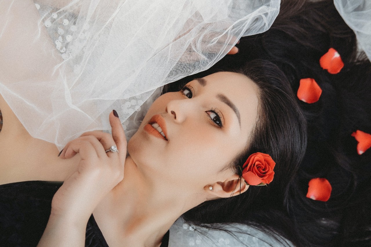 A bride with roses in her hair wears a round-cut diamond engagement ring.